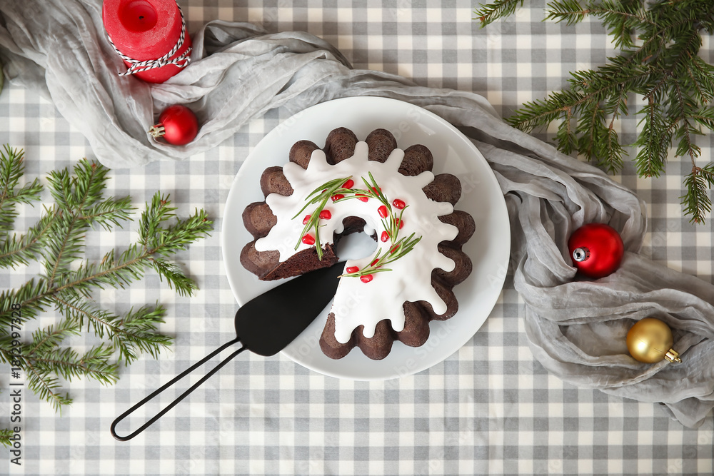 Obraz premium Tasty cut Christmas cake with spatula, candle, balls and fir tree branches on table