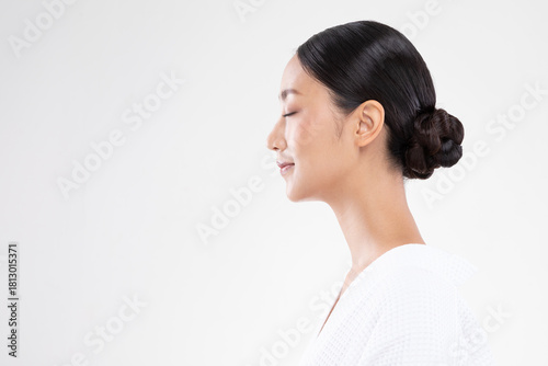 Asian serene woman profile portrait closed eyes bun hairstyle white robe meditative expression calm skin studio session wellness minimal background