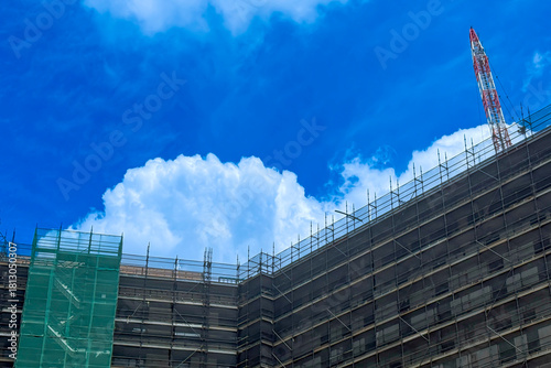 Photograph of a large white Cumulus cloud beginning to form over a multi storey tall building construction site in NSW, Australia.