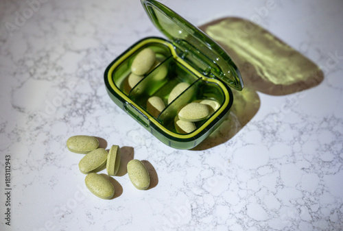 Close up of Green Supplement Pills in Green Travel Container