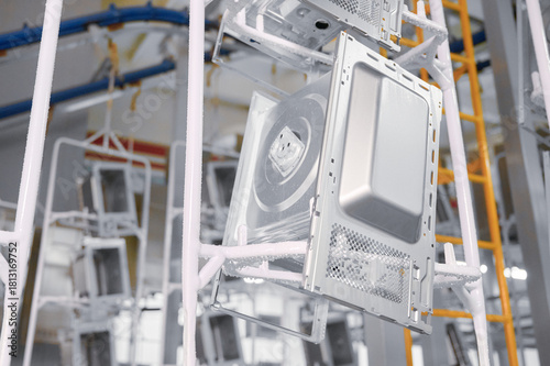 Microwave oven casings undergoing washing stage in a powder coating workshop on overhead conveyor system