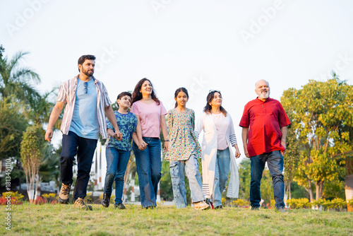 Indian family walking through green farm fields enjoying nature and joyful family togetherness