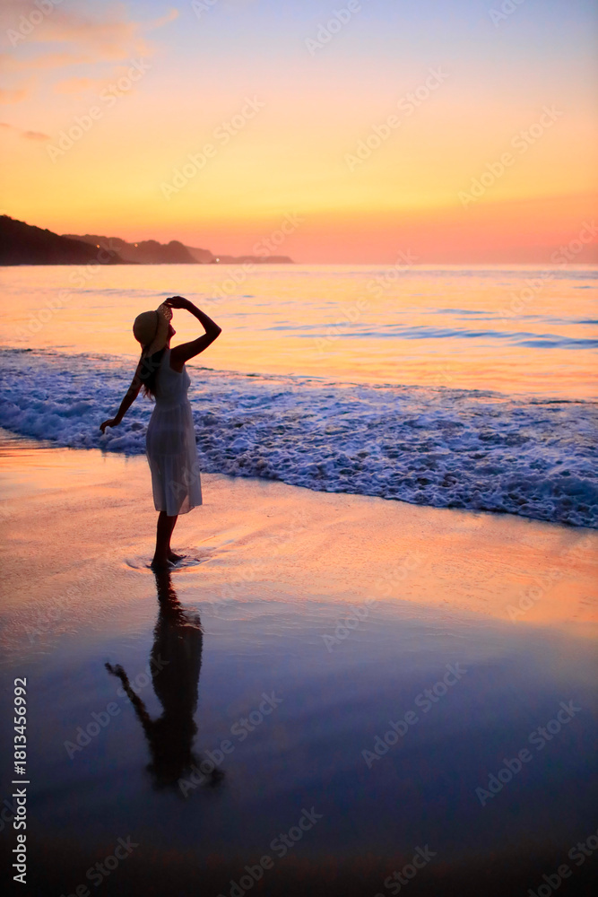 Fototapeta premium 夕焼けの海を眺める彼女