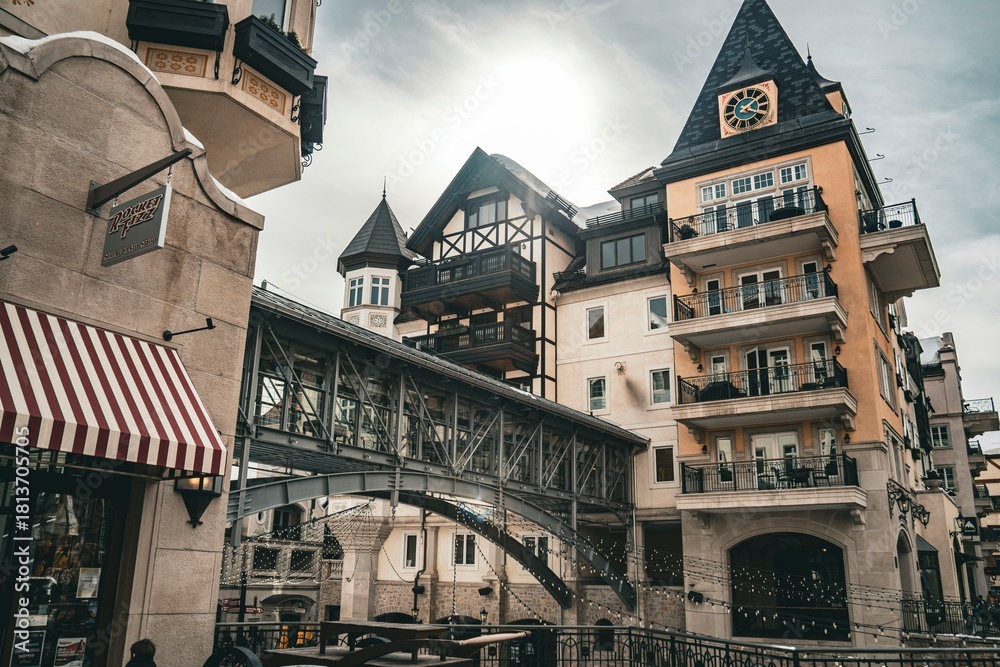 Naklejka premium Historic architectural scene featuring traditional European buildings with timber framing and a covered bridge in a charming old town setting