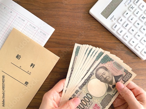 机上で紙幣を持つ女性の手と給料袋／給料日イメージ