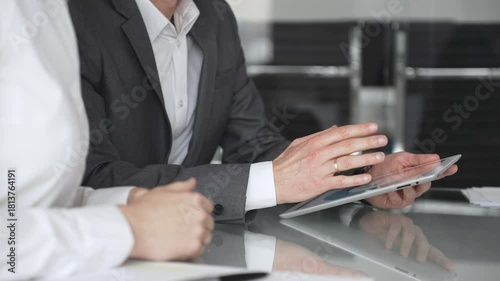 Business people collaborating during a meeting using a modern digital tablet, close up. Discussing strategies and analyzing data in a professional office environment