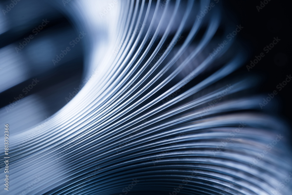 Obraz premium Abstract close-up of curved metallic lines creating a sense of warped space, motion and flowing geometry in cool blue tones. Photo
