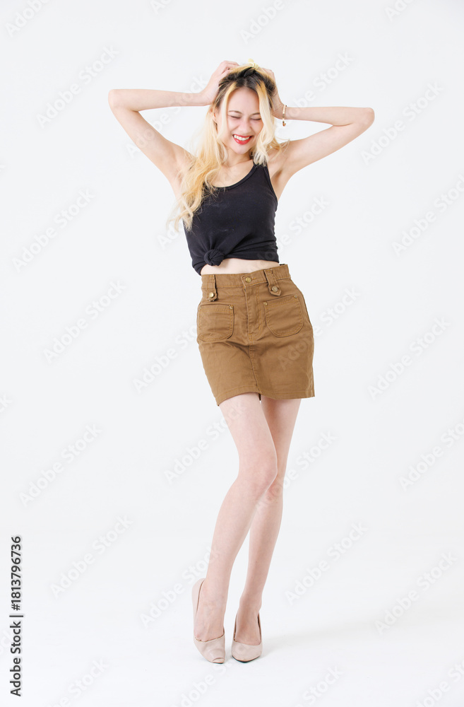 Fototapeta premium Asian beauty attractive woman blonde long hair stand wear black sleeveless top brown short skirt on white background studio portrait fashion street outfit trendy style pose look at camera full length.