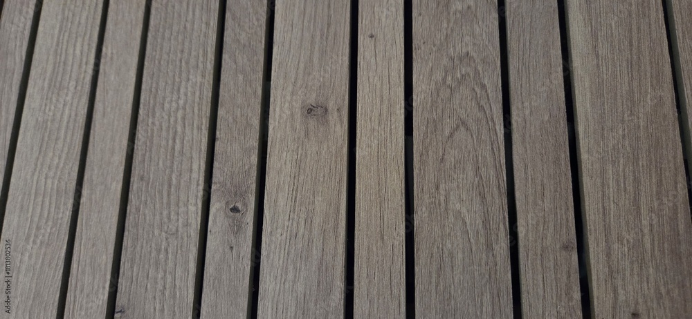 Fototapeta premium Aligned wooden planks, weathered by time and the elements. Their gray-brown tone and natural grain offer a rustic and soothing aesthetic, ideal for outdoor settings or organic design.