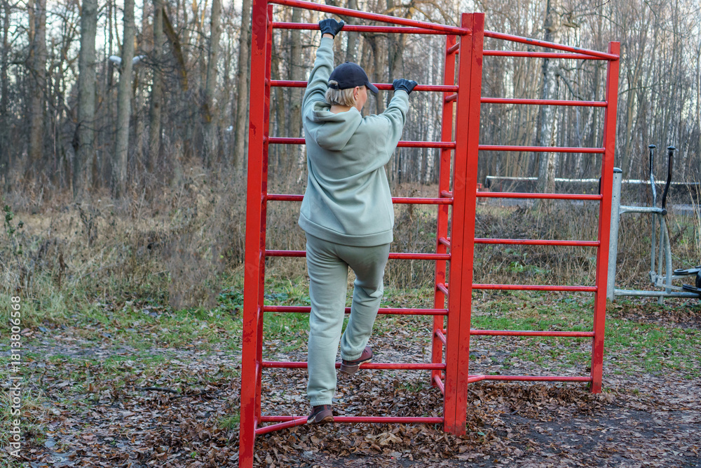 Obraz premium Woman exercising on outdoor fitness equipment in autumn