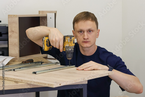 Wallpaper Mural Man drilling screws into drawer runner on furniture part Torontodigital.ca