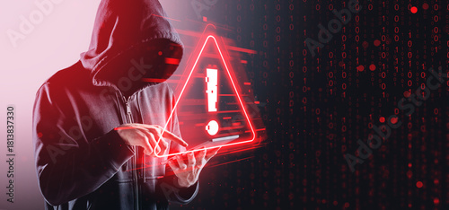 Hacker in hoodie using tablet with digital warning sign and bina