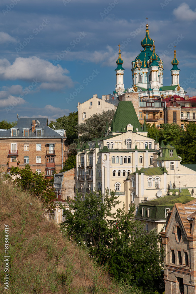 Obraz premium Majestic baroque St Andrew's Church with green domes rises above historic buildings on Andriivskyi Descent in Kyiv Ukraine creating a beautiful famous capital city landmark landscape view