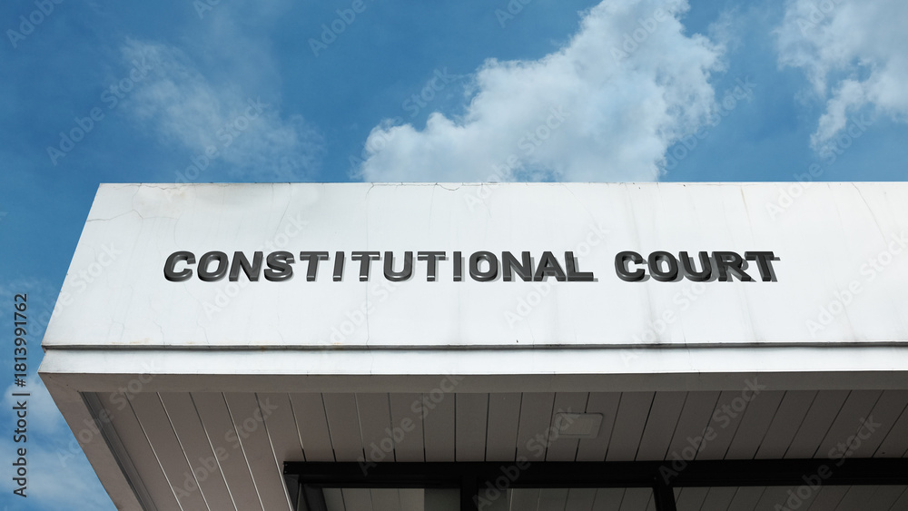 Obraz premium Constitutional Court word sign displayed on a building under a clear blue sky, representing judiciary, legal authority, government, law, and public administration facilities