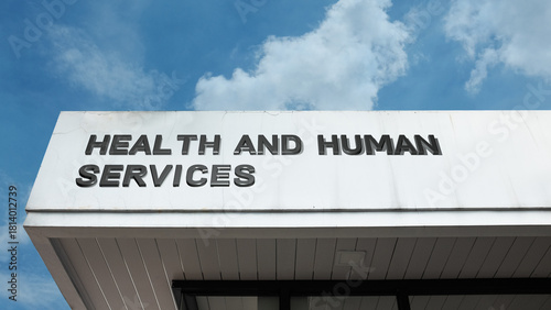 Health and Human Services sign displayed on a building against a clear blue sky, symbolizing public welfare, social support, medical aid, and civic aid