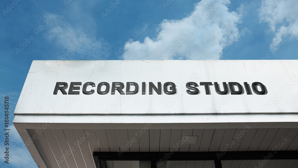 Obraz premium Recording Studio word signage on a commercial or media building under a blue sky, symbolizing music production, audio engineering, media creation, sound, and entertainment industry