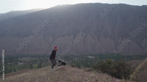 A girl walks with a dog at dawn in the mountains. Kyrgyzstan