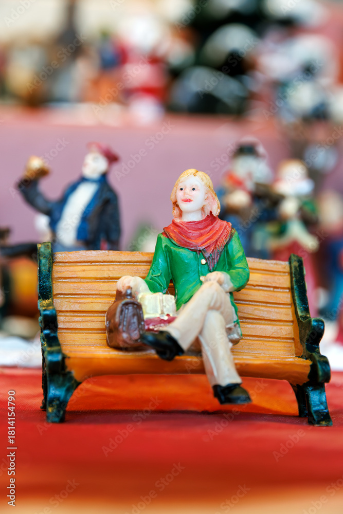 Obraz premium Festive Christmas figurine of a smiling woman sitting on a bench with gifts.