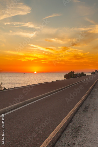 This stunning image captures the Howard Frankland Bridge at sunset, showcasing vibrant sky colors reflected across the calm coastal waters. 