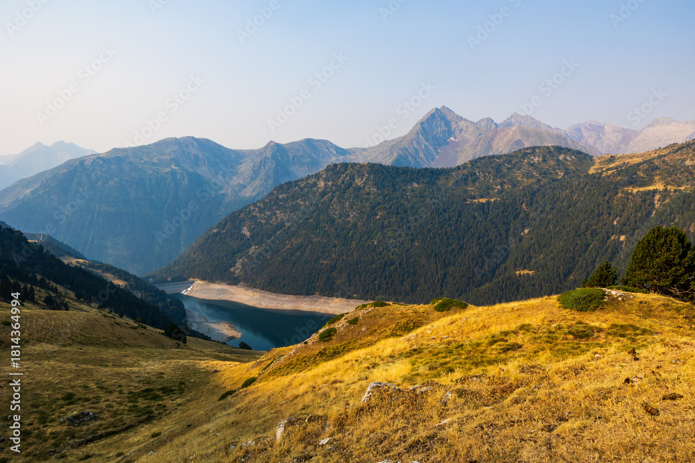 Fototapeta premium Low water level of Lac de l’Oule at sunrise, seen from a hiking trail between Col de Portet and Refuge du Bastan