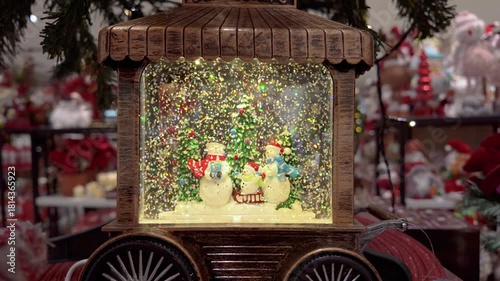 A charming vintage wooden train case hosts a glittering snow globe scene with cheerful snowmen.