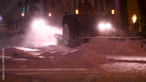 Large snow tractor at work on the evening streets of the city