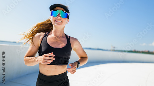 Woman running in activewear with sunglasses on a track
