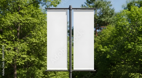 Two blank vertical banners on a pole surrounded by green trees