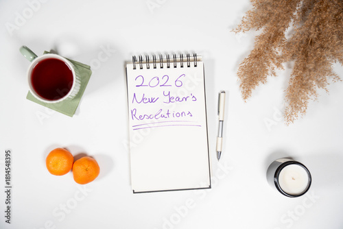 2026 New Year's Resolutions notebook with fresh tangerines and tea. Symbolizes health goals, diet changes, and a fresh start for the upcoming year.