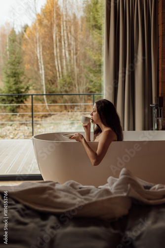 Enjoying a relaxing moment in a modern bathtub with a cup of tea