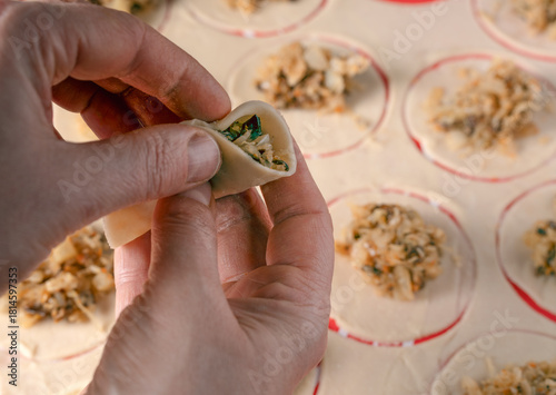 Close-up of hands skillfully pinching the dough to seal a traditional polish dumpling, filled with sauerkraut and mushrooms, on christmas eve