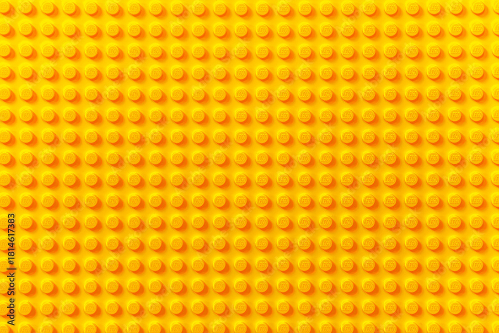 Naklejka premium Vibrant Yellow LEGO Brick Surface Texture Background