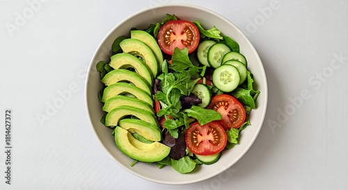 Overhead shot of a salad with avocado, tomato, and cucumber slices.