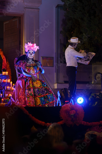 Day of the Dead Catrina Model Posing for Skeleton Artist beside Altar on Night Stage