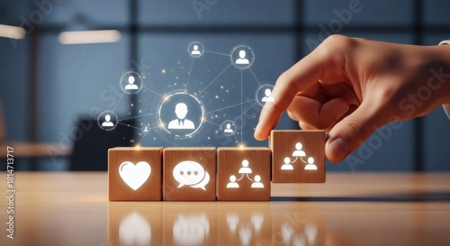 Human connection and team communication concept. Illuminated social icons on wooden blocks with hand selecting team structure symbol in modern office environment