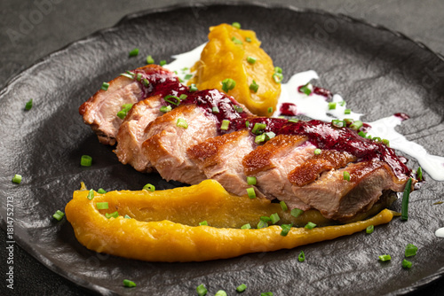 Tender seared duck fillet served with smooth pumpkin puree rich berry sauce and fresh herbs