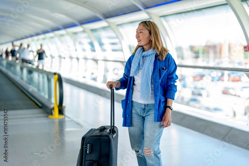 Woman walking with suitcase in bright airport terminal
