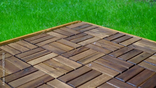 Composition of wooden parquet and grass in an outdoor setting during rainy weather. Focus and depth of field are selective. A romantic rainy landscape in the garden.