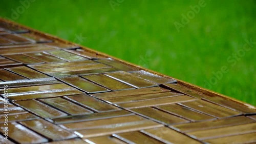 Composition of wooden parquet and grass in an outdoor setting during rainy weather. Focus and depth of field are selective. A romantic rainy landscape in the garden.