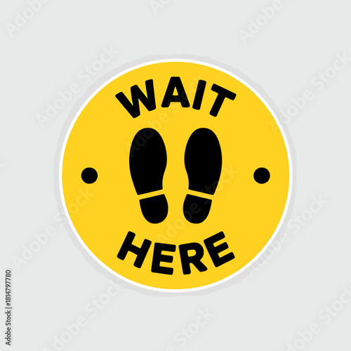 Yellow wait here floor sign with footprints for social distancing safety