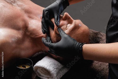 Deep buccal facial massage for man in spa salon closeup