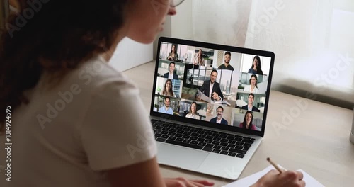 Businesswoman engages in videocall with group displayed on laptop screen