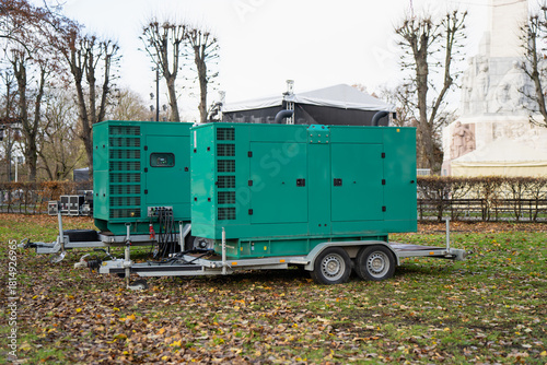 Heavy-duty portable generator units installed on trailer platforms in open grassy area featuring ventilation grids, wiring links and robust enclosures suited for temporary energy systems