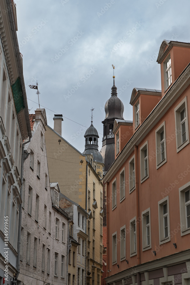 Obraz premium A view of historic buildings and church spires under a cloudy sky in Riga, Latvia