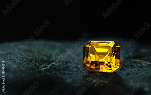 A yellow gemstone sits on a dark surface