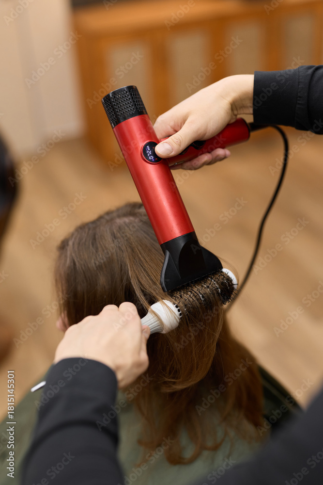 Fototapeta premium styling action captured, vibrant portrayal of stylist shaping hair amidst lively salon environment