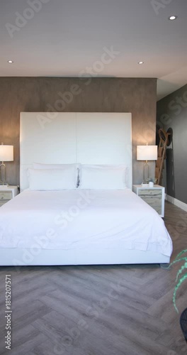 Vertical video: Camera starting panning left in bedroom revealing white bed and nightstands