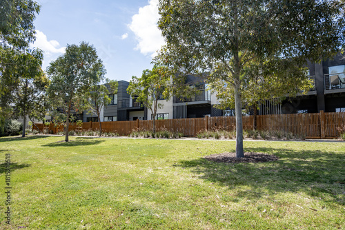 Foto Green space with trees, a lawn with a row of modern townhouses in a suburban Melbourne with a timber boundary fence