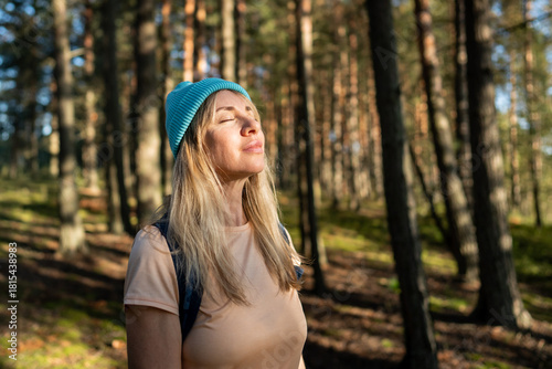Tableau sur toile Relaxed woman resting with closed eyes warming in sunlight during forest walk