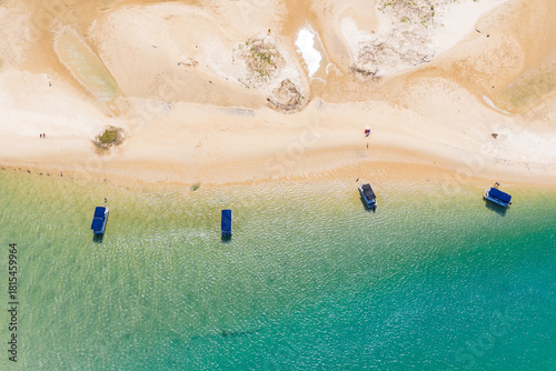 Aerial view of 4 small pleasure boats anchored in turquoise water off a coastal beach